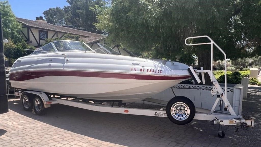 A two-person Starcraft fishing boat with rod holders and storage space resting on a boat trailer.