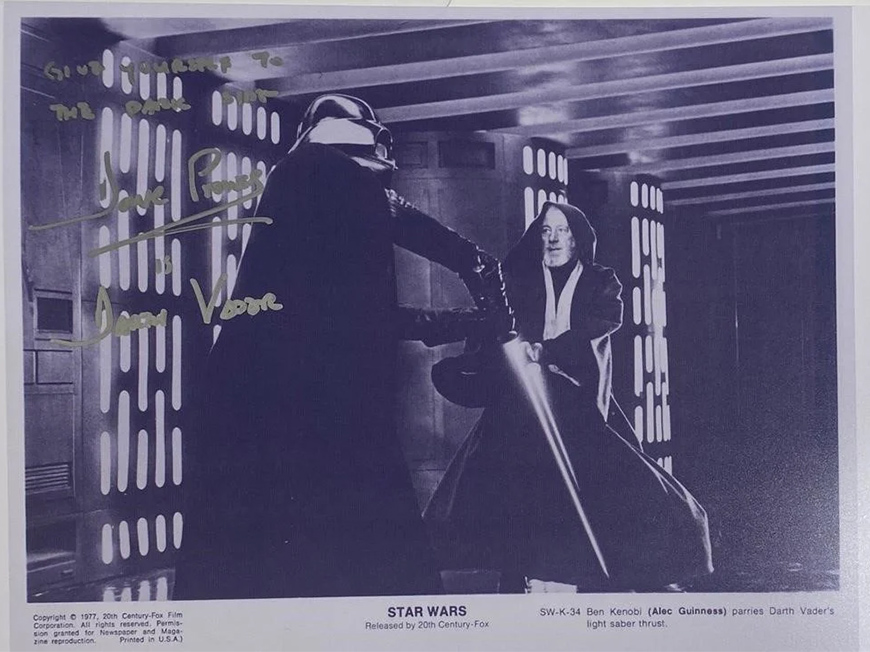 Black and white photo of characters Ben Kenobi and Darth Vader parrying with light sabers.